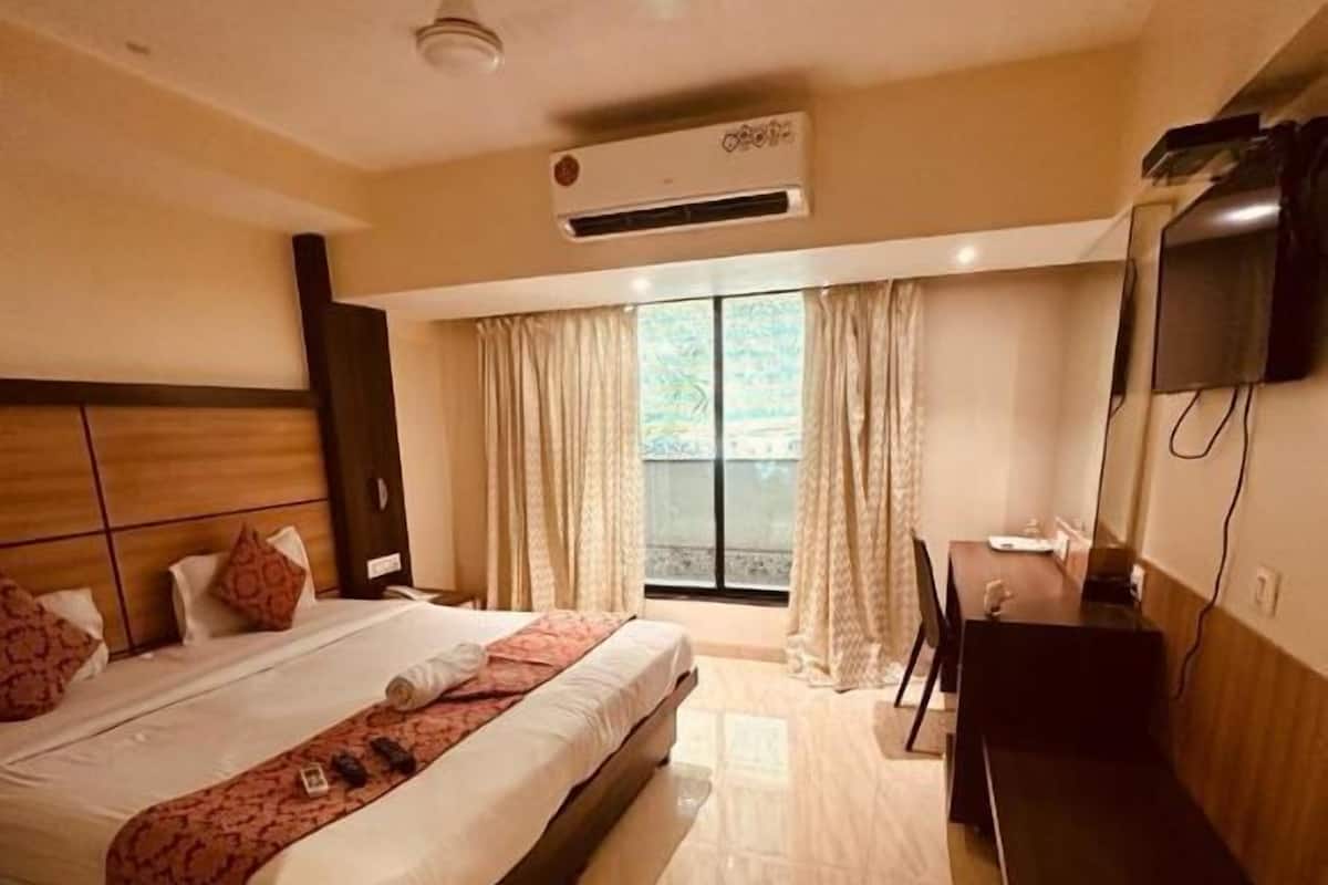 A hotel room with a bed, a desk, and a TV.