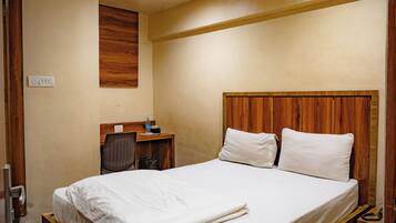 A bedroom with a wooden bed frame, a nightstand, a desk, and a ceiling fan.