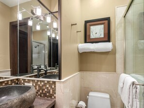 A bathroom with a stone sink, a toilet, a framed picture on the wall, and a towel rack. - Top of the Village~Leaf 103~Ski-in/out~HT~Pool~Grill~Parking (Snowmass Village)