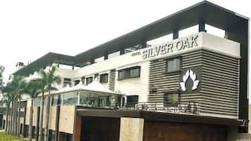 Ein Hotel namens Silver Oak mit moderner Architektur, das ein markantes Logo und einen überdachten Außenbereich zeigt.