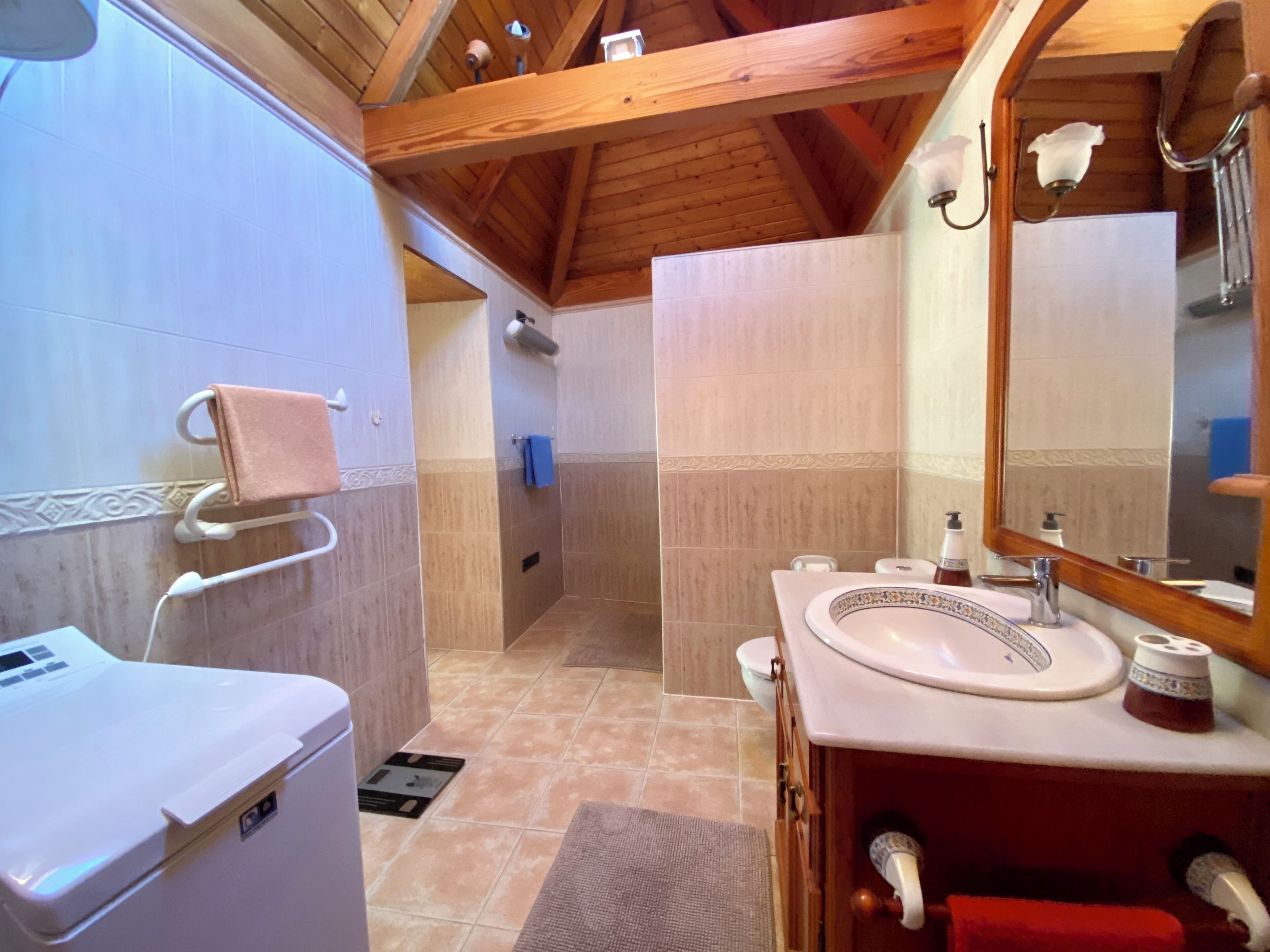 Un baño con un lavamanos blanco, un espejo y un toallero.