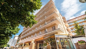 A multi-story hotel with balconies, a glass entrance, and a brick facade. - Hotel Boutique Can Colom (Lloret de Mar)