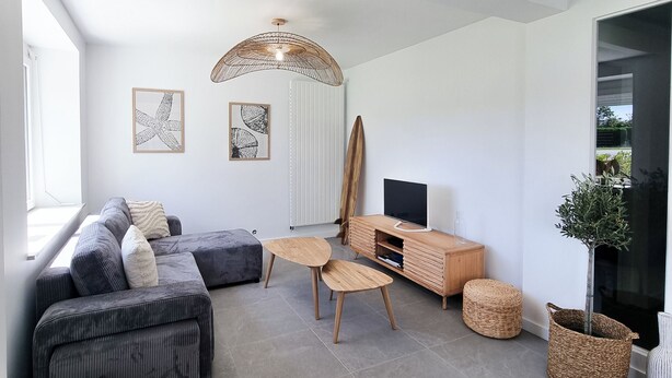 Una sala de estar moderna con un sofá modular, una mesa de centro de madera y un mueble para televisión.