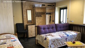 A cozy room with two beds, a sofa, a chair, a small table, and a radiator. - Radlerzimmer mit Separatem Bad Außerhalb des Zimmers. Sehr Gemütlich (Ziethen)