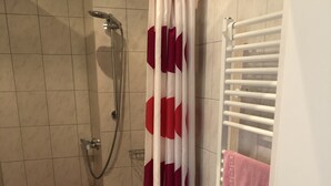 A bathroom with a shower, a red and white patterned shower curtain, a checkered floor, and a towel rack with a pink towel. - Radlerzimmer mit Separatem Bad Außerhalb des Zimmers. Sehr Gemütlich (Ziethen)
