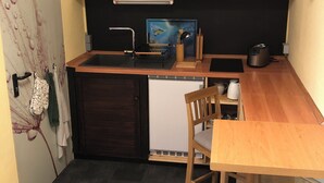 A compact kitchen with a wooden table, chairs, a sink, and a refrigerator. - Radlerzimmer mit Separatem Bad Außerhalb des Zimmers. Sehr Gemütlich (Ziethen)