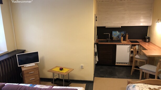 A compact room with a bed, a small table with a TV, a kitchenette, and a desk. - Radlerzimmer mit Separatem Bad Außerhalb des Zimmers. Sehr Gemütlich (Ziethen)
