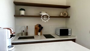 A kitchen with a microwave, sink, and wooden shelves. - La Balinaise (Chaweng Noi)