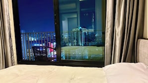Une chambre d’hôtel avec une grande fenêtre donnant sur une vue panoramique de la ville la nuit.