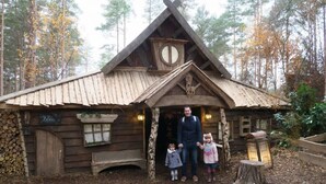 A rustic wooden cabin with a steeply pitched roof, a circular window, and a wooden door.