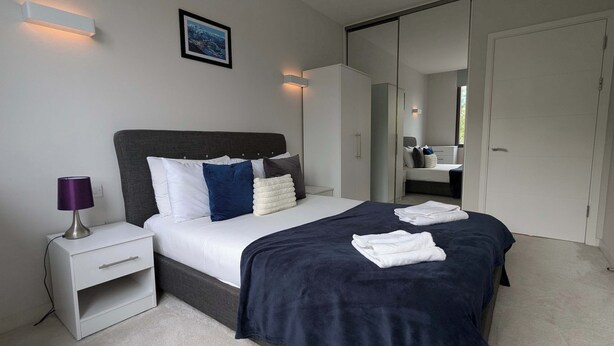 A modern bedroom with a bed, bedside table, and wardrobe.