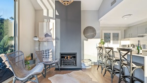 A modern kitchen with a fireplace, bar seating, and a view of the outdoors.