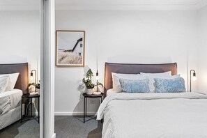 A modern hotel room with a large bed, a smaller bed, a bedside table with a lamp, a wall-mounted picture, and a small potted plant. - Ralphie’s Villa - 2 bed 2 bath with Valley Views (Kangaroo Valley)
