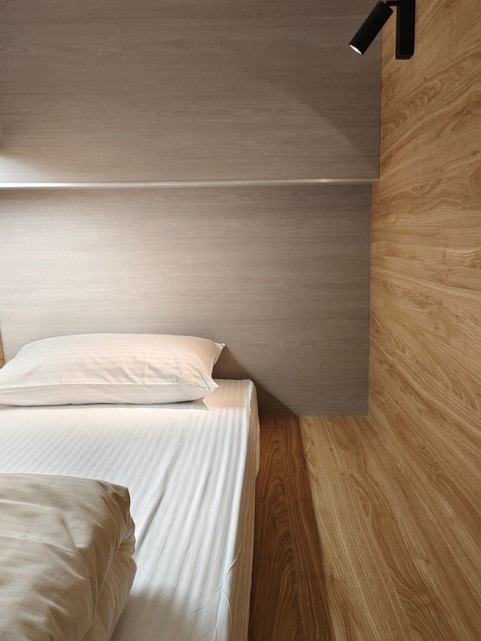 Ein Stockbett mit Kopfteil und einer Holzwand.
