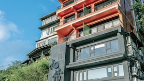 A multi-story building with balconies, large windows, and a prominent entrance with a metal gate.