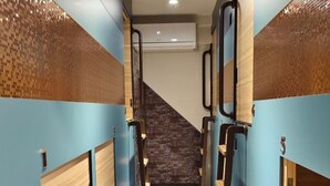 A corridor with lockers, a stone wall, and a ceiling light.
