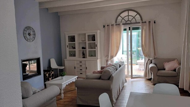 A living room with a sofa set, a dining table, a cabinet, and a large window with curtains. - Magnifique Maison 8/10 Personnes à Rully. Piscine Privée. Terrain de Boule (Rully)