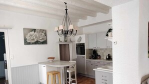 A compact kitchen with a central island, a dining area with chairs, and a chandelier. - Magnifique Maison 8/10 Personnes à Rully. Piscine Privée. Terrain de Boule (Rully)