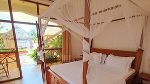 A wooden four-poster bed with a canopy, a wooden floor, and a view of a thatched-roof building outside. - Mimi na wewe villa (Nungwi)