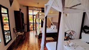 A room with a wooden floor, a bed with a canopy, a ceiling fan, and a view of an outdoor area with a table and chairs. - Mimi na wewe villa (Nungwi)