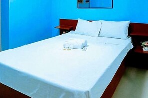 A hotel room with a bed, a nightstand, a small table with a plant, and a mirror on the wall. - Jeanines Travellers Inn by RedDoorz (Morong)