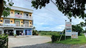 A multi-story building with various shops on the ground floor, including a sports apparel store and a clinic. - Jeanines Travellers Inn by RedDoorz (Morong)