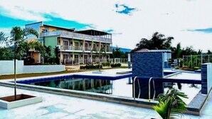 A hotel with a swimming pool, a multi-story building, and a landscaped garden. - Jeanines Travellers Inn by RedDoorz (Morong)