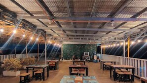 An indoor dining area with tables and chairs, a green wall with plants, and a ceiling with exposed beams and lighting. - Jeanines Travellers Inn by RedDoorz (Morong)