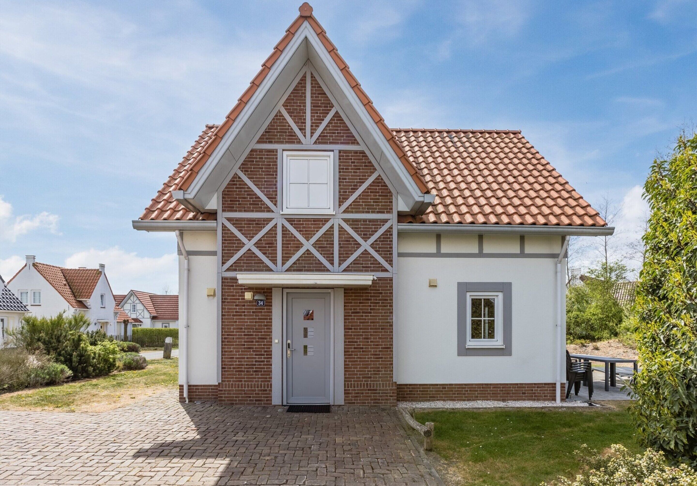 Een twee verdiepingen tellend huis met een puntig dak, een voordeur en een klein raam aan de zijkant.