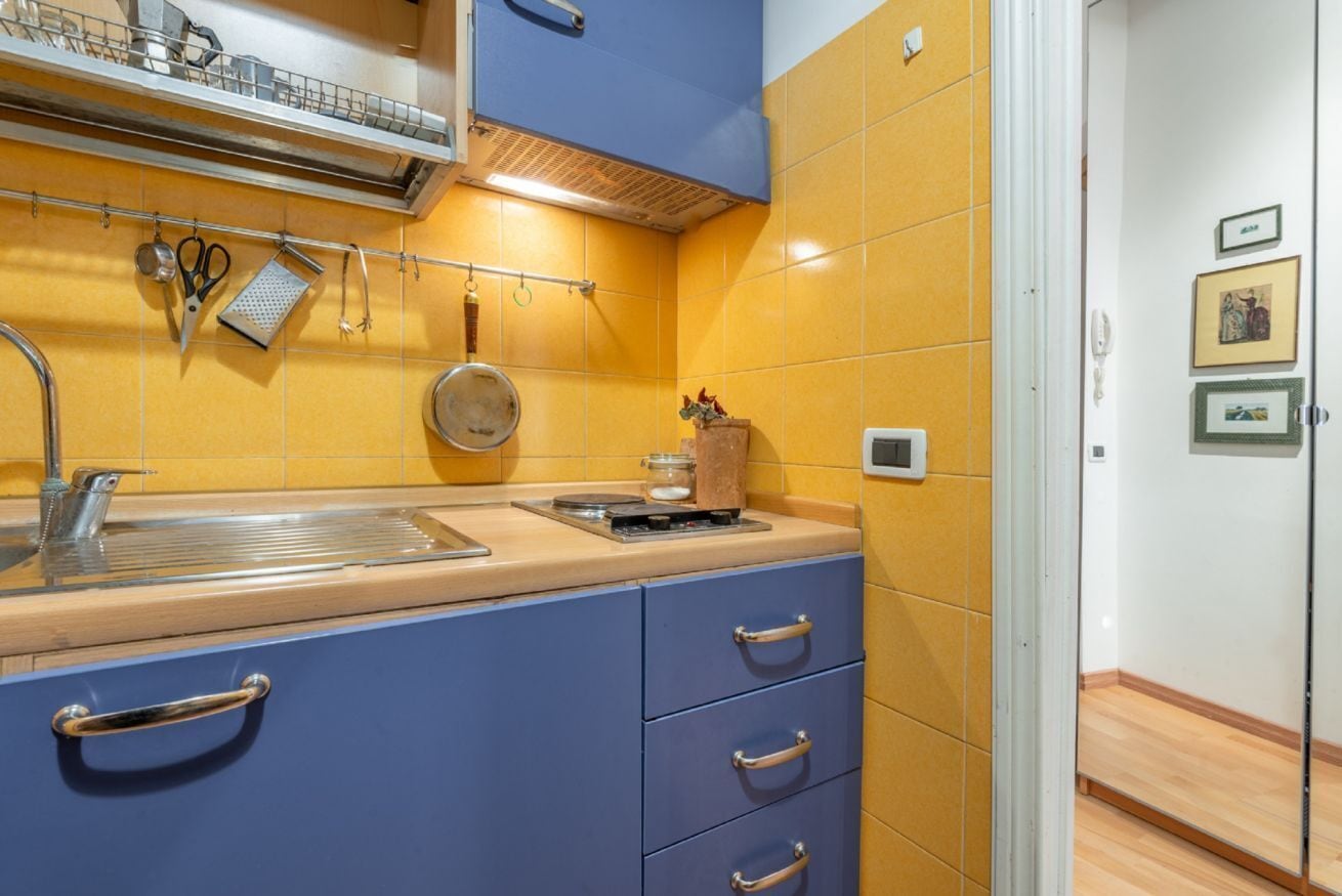 Una cocina con lavamanos, estufa y armarios azules.