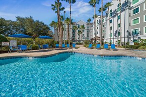A swimming pool with blue water, surrounded by lounge chairs and palm trees. - * Free Parking & Disney Shuttle * King Bed & Queen Beds w/Adjustable Base (Orlando)