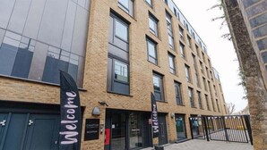 Un edificio moderno con fachada de ladrillo, zona de recepción y un toldo negro con la palabra 'Welcome'.