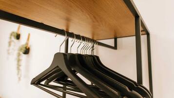 A black hanger rack with multiple hangers against a wooden ceiling.