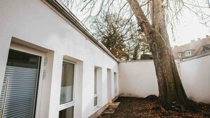 A white building with a large tree in front. - Staylight City-Loft | private parking | trade fair (Hannover)