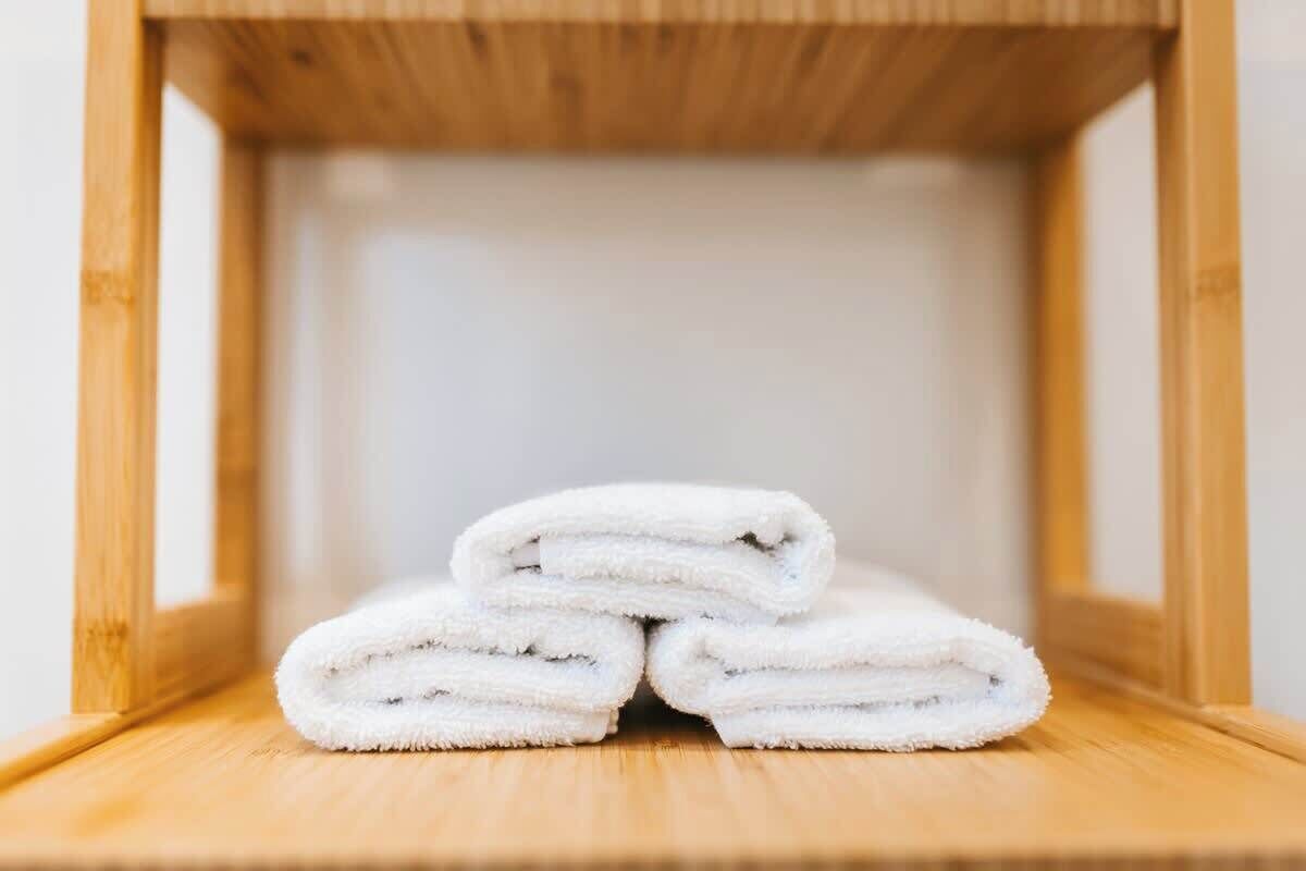 A stack of white towels on a wooden shelf.