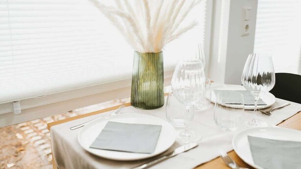 A dining table set with plates, cutlery, and a vase with white flowers. - Staylight City-Loft | private parking | trade fair (Hannover)