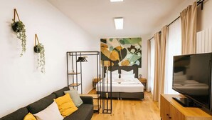 A modern room with a bed, a TV, a sofa, and a wooden floor. - Staylight City-Loft | private parking | trade fair (Hannover)
