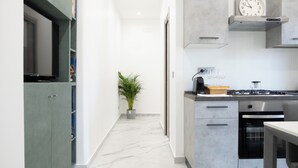A modern kitchen with a marble floor, a built-in stove, and a clock on the wall. - Adelina House | Quiet and Central Flat near University and Subway (Catania)