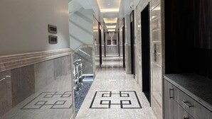 A modern hallway with marble flooring, recessed lighting, and a geometric pattern on the floor. - HOTEL JIA INTERNATIONAL (Patna)