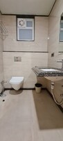 Un baño con inodoro, lavamanos y una pequeña ventana sobre el inodoro.