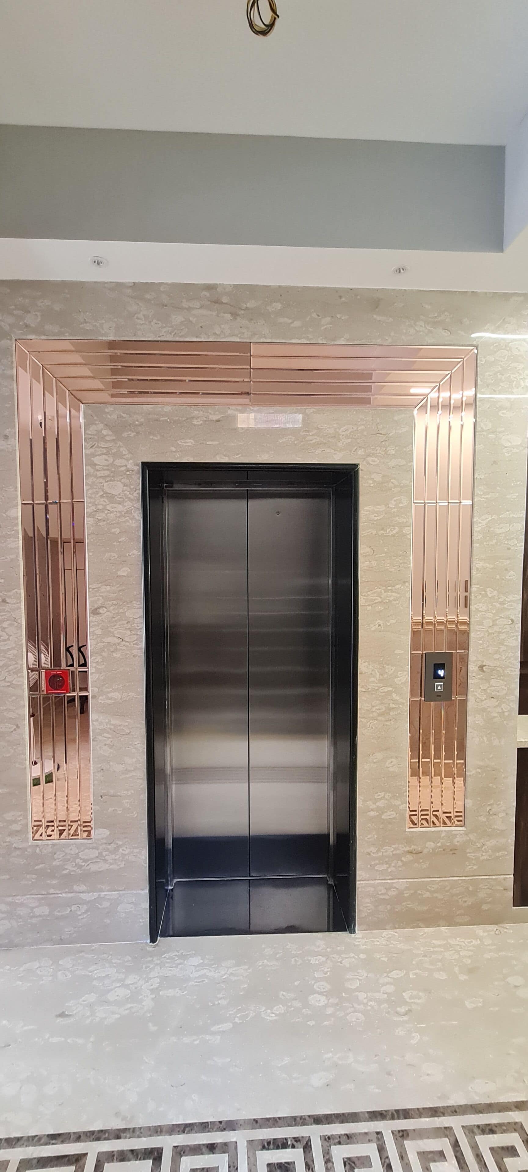 An elevator with a metallic finish, a control panel, and a patterned floor.