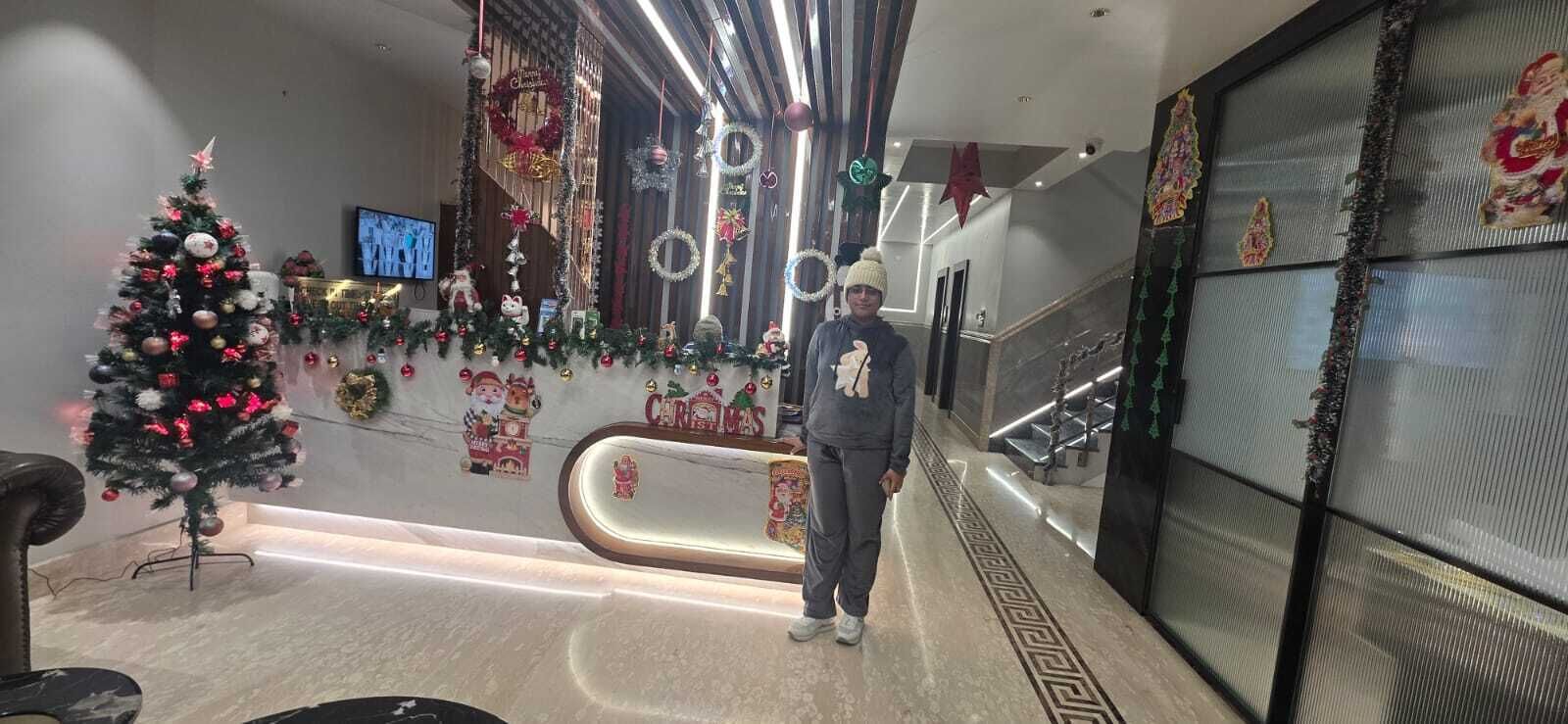 Een hotel lobby met een kerstboom, een receptiebalie en een trap.