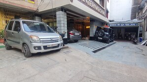 A parking area with a silver van, a black SUV, and a blue scooter. - HOTEL JIA INTERNATIONAL (Patna)