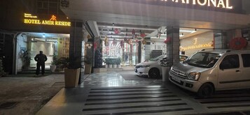 Entrada de un hotel con un paso de peatones que conduce a una furgoneta blanca estacionada a la derecha.