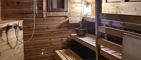 A sauna room with wooden walls, a bench, a small window, and a heater.