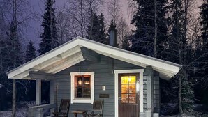 A small cabin with a porch, two windows, and a door.