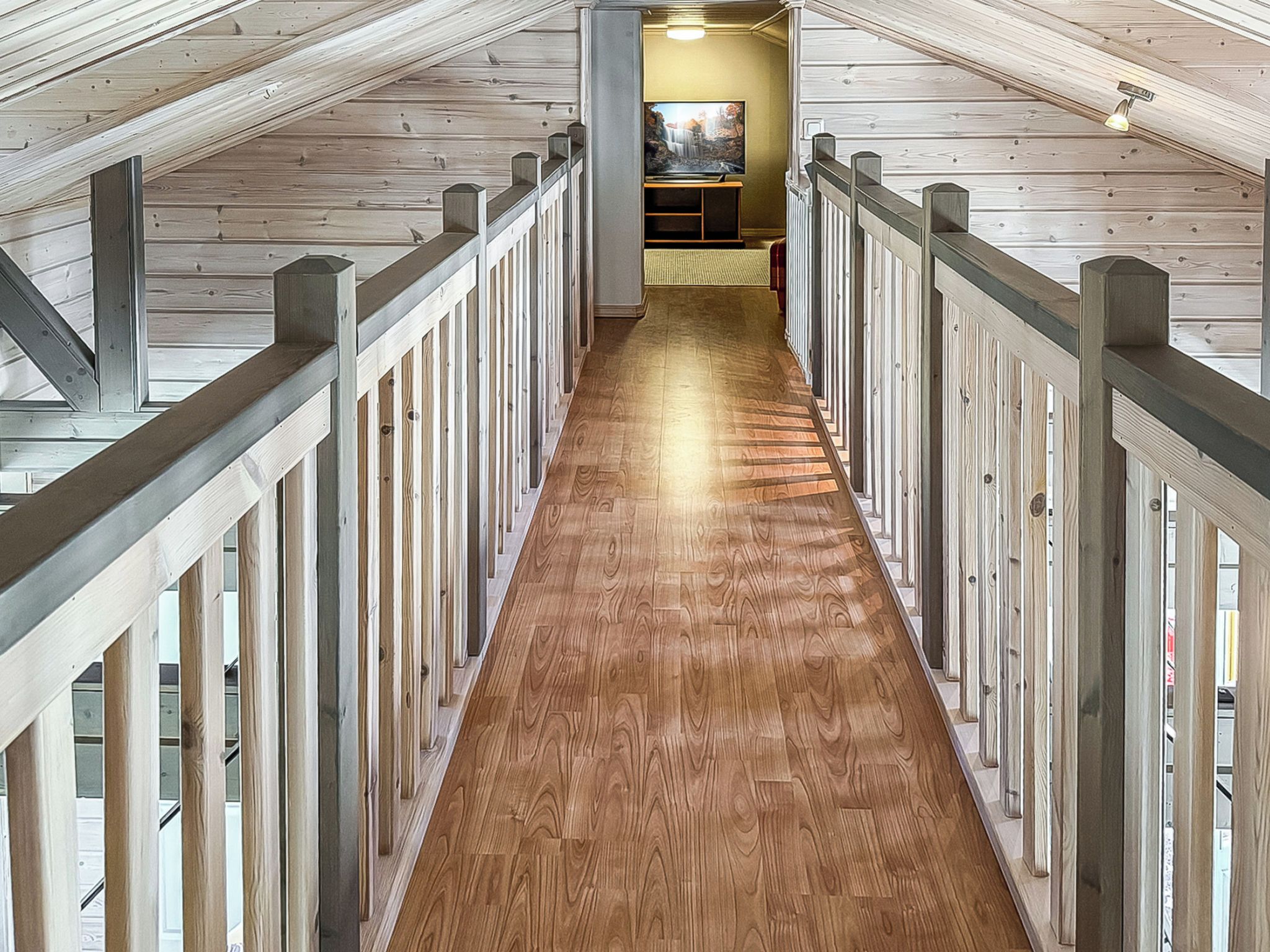 A wooden interior with a central corridor leading to a room with a television.