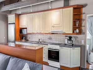 A compact kitchen with white cabinetry, a built-in oven, and a coffee maker. - Villa taikavuosseli by Interhome (Kuusamo)