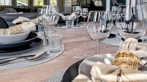 A dining table set with clear glassware, a candle, and a woven napkin.