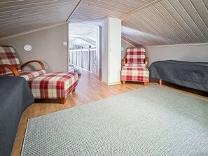 A room with two beds, a chair, and a view of a balcony. - Villa taikavuosseli by Interhome (Kuusamo)